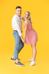 Poster - Happy dancing young couple on color background