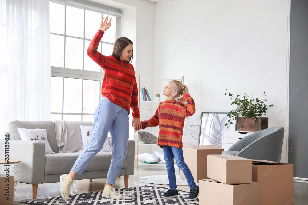 Happy mother and her little daughter dancing at home