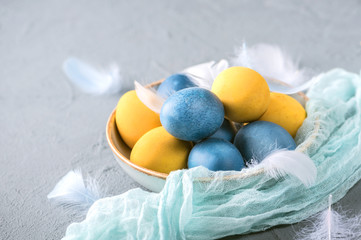 Colorful easter eggs with feathers on light background