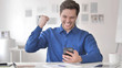 © stockbakers - Casual Adult Man Celebrating Success on Smartphone