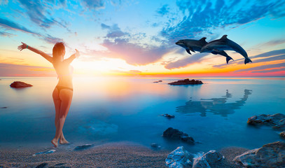 Aufkleber - Silhoutte of beautiful dolphin jumping up from the sea at sunset -   Happy slim girl in red and black bikini with raised up arms on the seashore in Alanya, Turkey