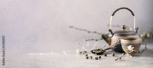 Cuadros en Lienzo Black and brown iron teapot and tea cups, blossom flowers cherry branch on gray background
