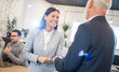 © Bojan - Smiling young businesswoman shaking hands with senior businessman in office