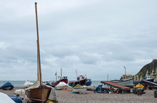 The Local Fishing Fleet Stranded On The Pebble Beach At Beer In South Devon, UK. Vessels Are Towed To And From The Sea By Tractor