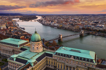 Wall Mural - Budapest, Hungary - Aerial view of Buda Castle Royal Palace with Szechenyi Chain Bridge, Parliament and colorful clouds at golden sunrise