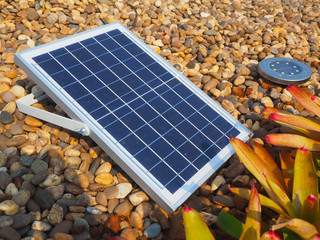 blue solar panel system and spotlight lamp on brown rock in the garden using for energy saving concept