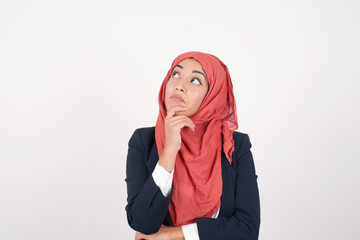 Wall Mural - Portrait of thoughtful smiling girl keeps hand under chin, looks sideways, thinking or wondering about something with interest, dressed casually, poses against gray studio. Taking decisions concept.