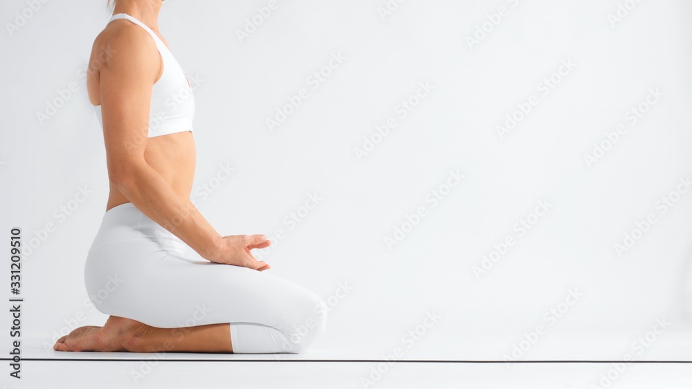 Unrecognizable woman sits on youga mat in profile in white space  - obrazy, fototapety, plakaty 