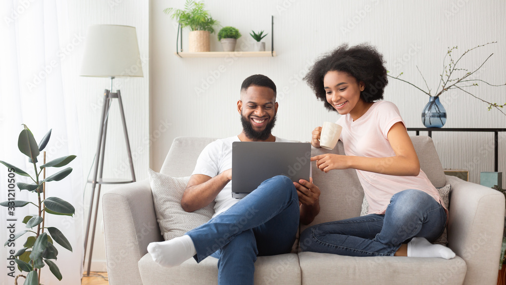African american couple on couch with laptop - obrazy, fototapety, plakaty 