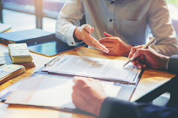 businessman puts signature on contract at business meeting and passing money after negotiations with