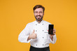 © ViDi Studio - Smiling young bearded male chef cook or baker man in white uniform isolated on yellow background. Cooking food concept. Mock up copy space. Hold mobile phone with blank empty screen showing thumb up.