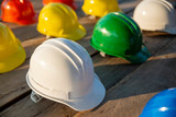 Fototapeta Sypialnia - Safety helmet (hard hat) for safety and health officer, engineer or architect place on old wooden floor. Multicolor safety hat (helmet) in construction site.Safety equipment concept.