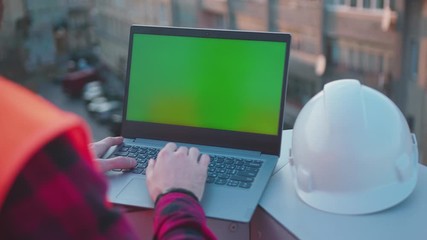 Wall Mural - Beautiful background hands man engineer using laptop computer with green screen on balcony helmet worker project occupation builder technology mock-up professional male safety computer slow motion