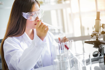 Wall Mural - attractive happiness scientist woman using microscope testing some blood sample at laboratory with l