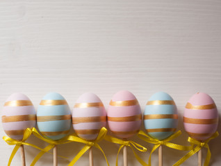 Wall Mural - Easter eggs blue and pink on a stick on a wooden background