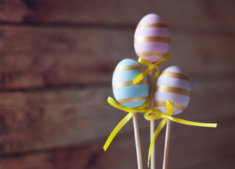 Wall Mural - Easter eggs blue and pink on a stick on a wooden background