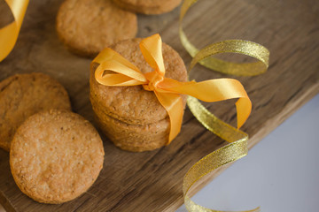 Wall Mural - Parmesan cookies with yellow ribbon on wooden background with fir and garland