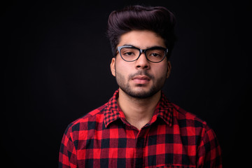 Young handsome Indian man against black background