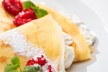 Wall Mural - close up view of tasty crepes with raspberries and whipped cream on plate