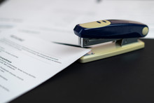 stapler and the documents files in office on the table, staple the paper sheets of resume and contracts