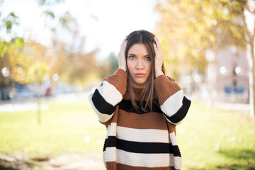 Woman plugging ears with hands does not wanting to listen hard rock or loud music. European Young  female ignoring noise or din covering her ears with hands avoiding loud sounds at street.