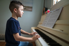 Young Boy Playing The Piano At Home