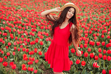 Happy Woman In Red Dress Standing On Red Tulips Field