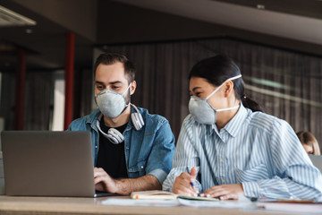 Sticker - Photo of multinational students in medical masks studying with laptop