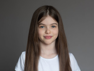 portrait of a beautiful smiling, little/ young brunette girl in a white t-shirt. close-up face of eu