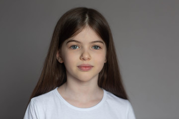 portrait of a beautiful smiling, little/ young brunette girl in a white t-shirt. close-up face of eu