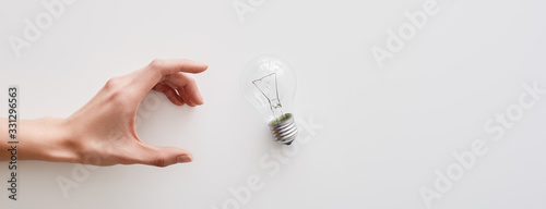 Photographie Female hand near an incandescent light bulb