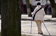 © Irik - elderly woman with walking sticks walks down the street on a sunny day