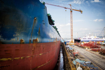 Poster - A large tanker kargo ship is being renovated and painted in shipyard dry dock.