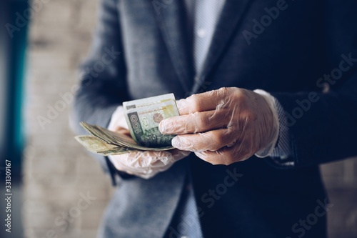 Cuadros en Lienzo Man counting Polish zloty money banknotes in protective latex gloves