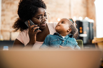 Afro American lady holding baby and talking on cellphone