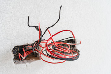 Protruding colorful wire and cable socket on white cement wall. unfinished install  .home repair.