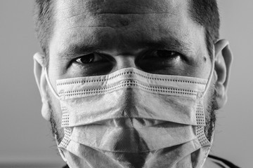 Close up black and white portrait of caucasian man adult wearing anti virus bacteria pollution protective mask head shot looking to the camera studio shot front view