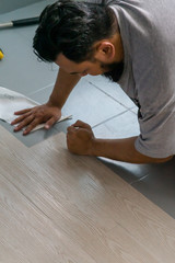 Kuala Lumpur, Malaysia - March 1, 2020: A man installing new vinyl tile floor, a DIY home project.