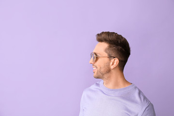 Wall Mural - Young man with stylish sunglasses on color background