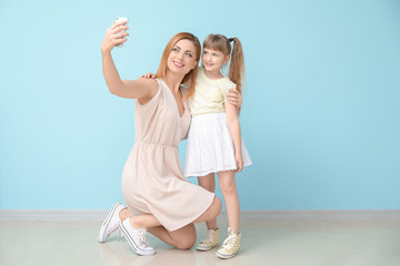 Poster - Woman and her little daughter taking selfie near color wall