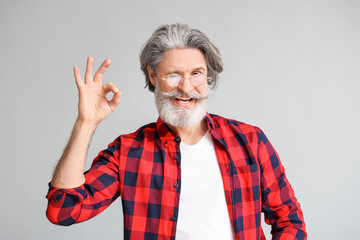 Canvas Print - Stylish elderly man showing OK gesture on grey background