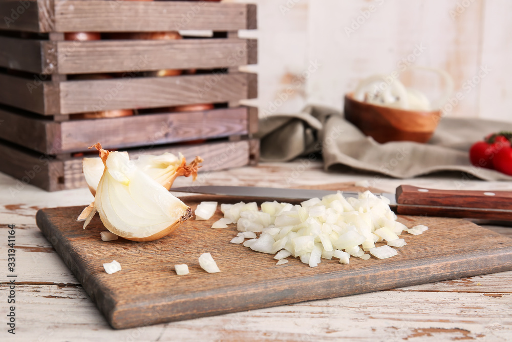 Board with fresh cut raw onion on wooden table