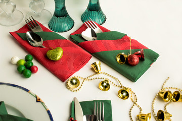 Wall Mural - Christmas green and red colors paper napkins folded in various shapes on white surface with cutlery set and christmas decoration