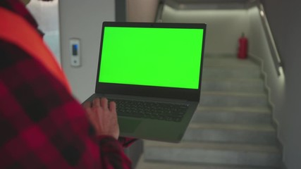Wall Mural - Hands young engineer using laptop computer with green screen inside building background stairs worker project occupation builder technology mock-up professional male computer slow motion