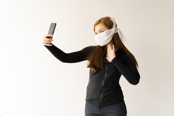 a woman protects herself from coronavirus using a mask on her face. Communication with family and friends via the Internet. Quarantine communication concept sitting at home.