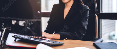 Fotografía Confident asian businesswoman relaxing looking at technology of desktop computer while sitting on office desk