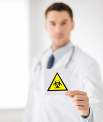 health, medicine and pandemic concept - male doctor holding boihazard caution sign