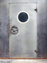 Door With Porthole. Metal Door With A Round Window On Rusty Metal Wall Background