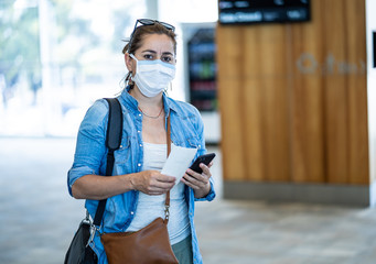 Wall Mural - Coronavirus outbreak travel restrictions. Traveler with mask at airport affected by travel ban and flight cancellations and Borders shutdowns.