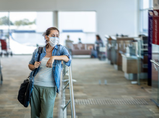 Wall Mural - Coronavirus outbreak travel restrictions. Traveler with mask at airport affected by travel ban and flight cancellations and Borders shutdowns.